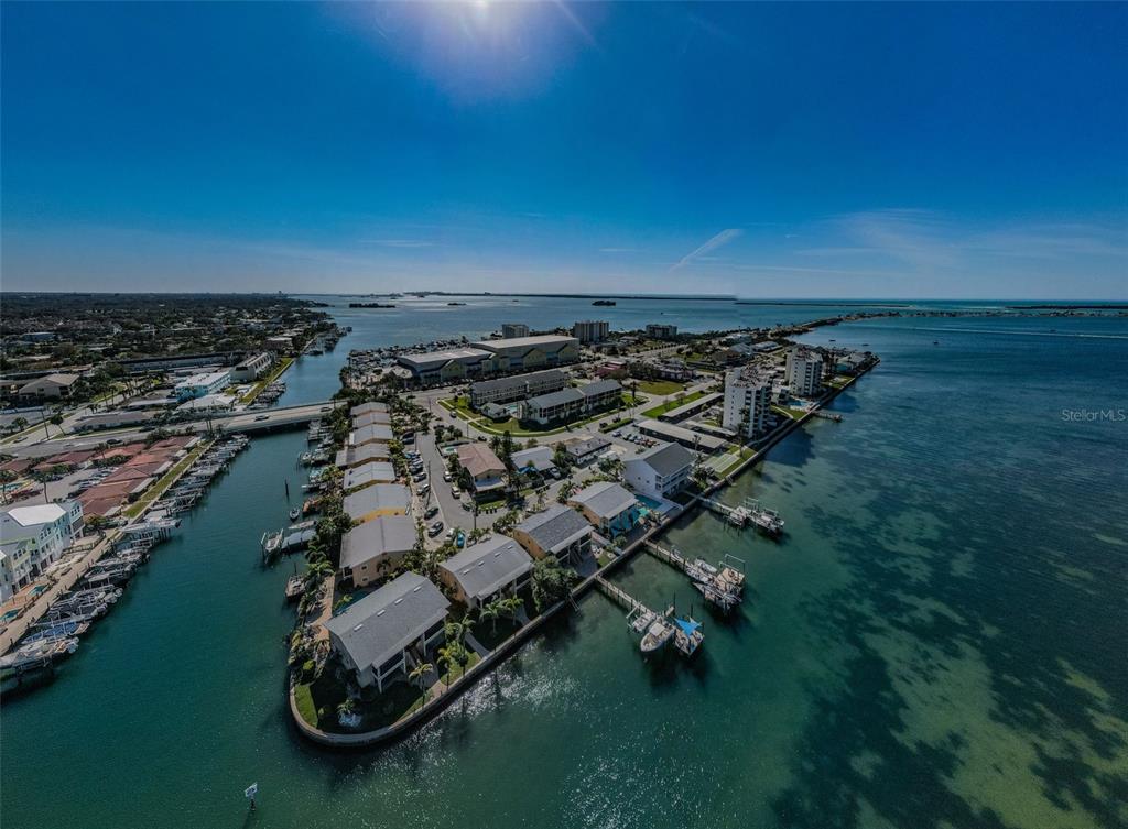 An aerial view shows a waterfront residential complex with boat slips and surrounding coastal waters — 2675 ST JOSEPHS DRIVE E UNIT B, DUNEDIN, FL
