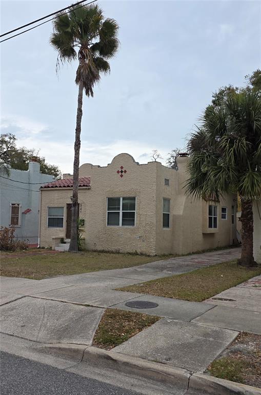 A single-story stucco house with a mission-style roofline and palm trees in the front yard — 847 S RIDGEWOOD AVENUE, DAYTONA BEACH, FL