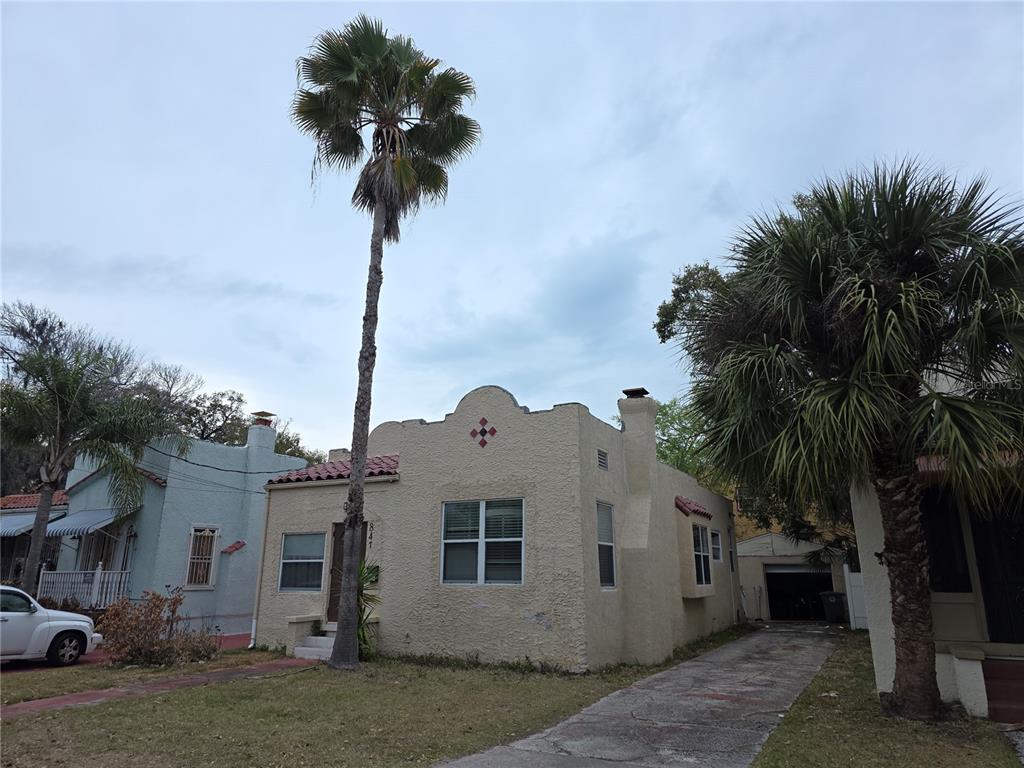 A single-story stucco house with a mission-style roofline and a palm tree in the yard — 847 S RIDGEWOOD AVENUE, DAYTONA BEACH, FL