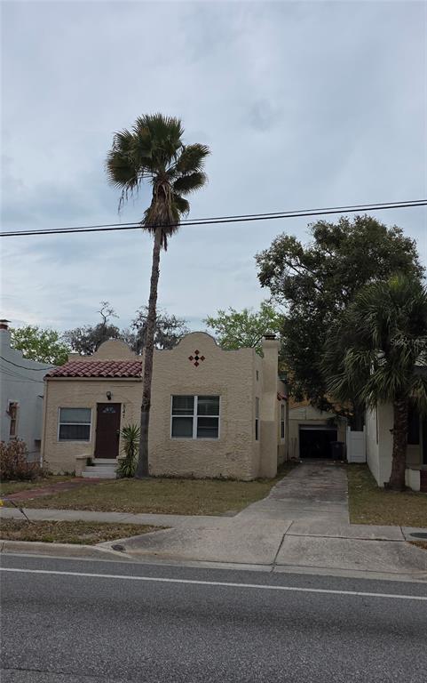 A single-story stucco house with a mission-style roofline and a tall palm tree in front — 847 S RIDGEWOOD AVENUE, DAYTONA BEACH, FL