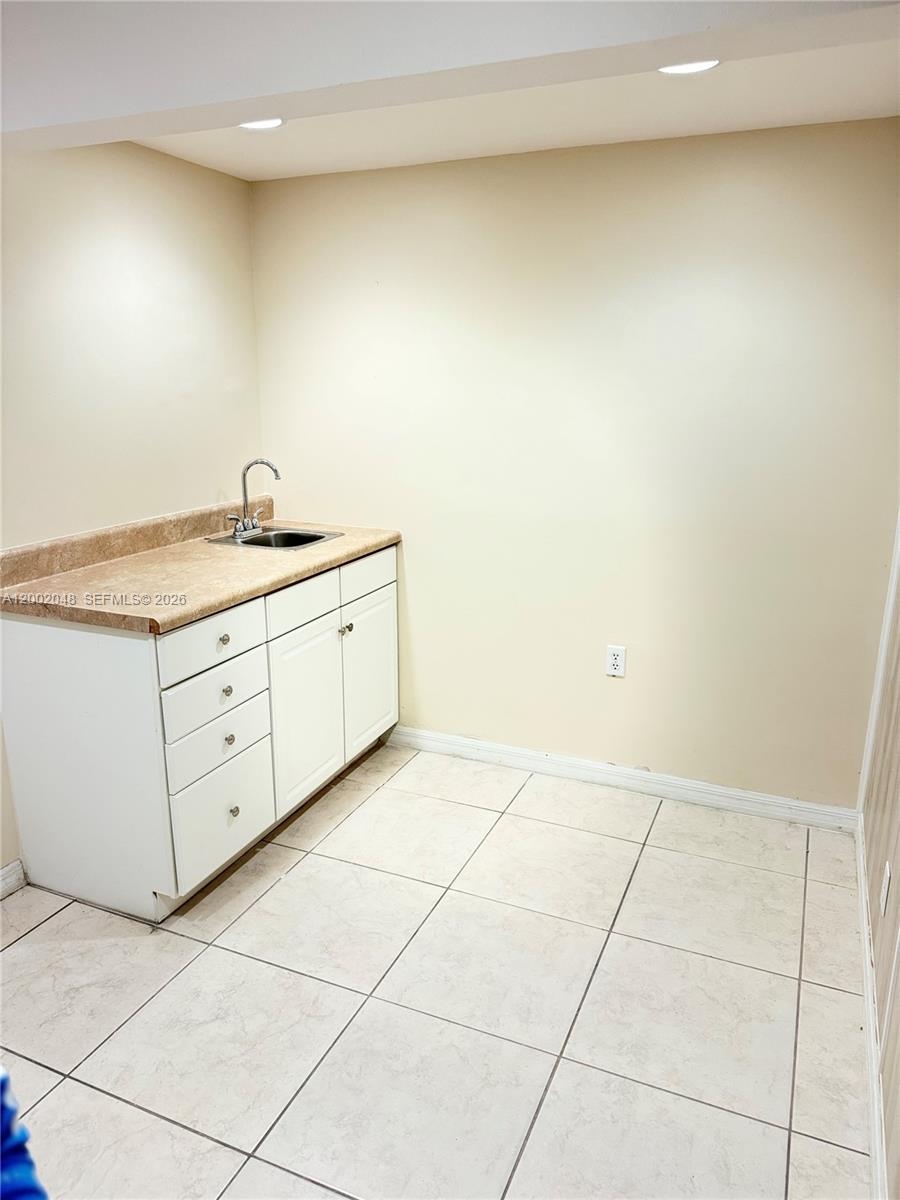 A small room features a white cabinet base with a sink and beige countertop — 706 N 7th St, Fort Pierce FL 34950, FORT PIERCE, FL