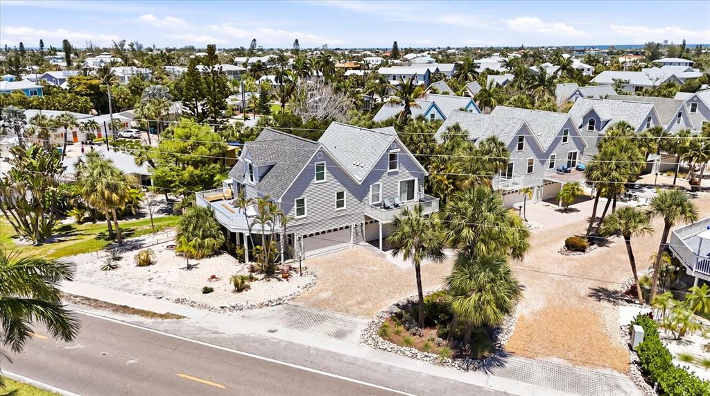 An aerial view shows a gray, multi-story coastal house with a garage and palm trees — 6325 GULF DRIVE, HOLMES BEACH, FL