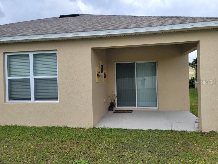 The exterior of a house features a covered patio, sliding glass doors, and a window — 376 TANGLEWOOD DRIVE, DAVENPORT, FL