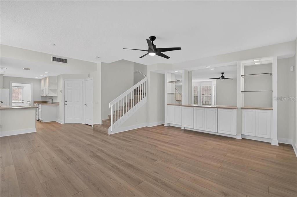 A living room with light wood floors, a white staircase, and built-in white cabinetry — 5975 GIARDINO LANE, SARASOTA, FL