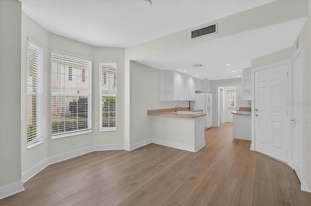 A bright dining area features wood-look flooring, a bay window, and an open kitchen — 5975 GIARDINO LANE, SARASOTA, FL