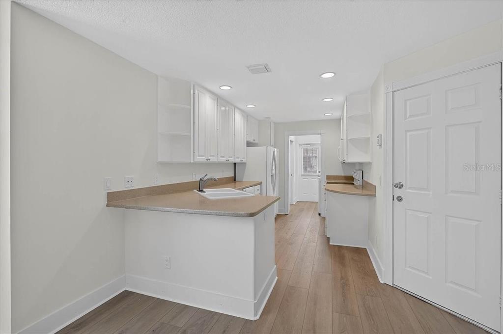 A kitchen with white cabinets, tan countertops, and wood-look flooring — 5975 GIARDINO LANE, SARASOTA, FL