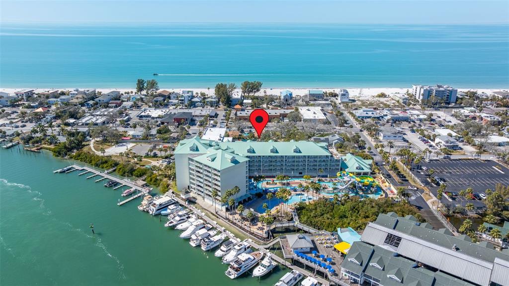 An aerial view shows a large waterfront hotel with a pool, waterslide, and boat slips — 399 2ND STREET UNIT 216, INDIAN ROCKS BEACH, FL