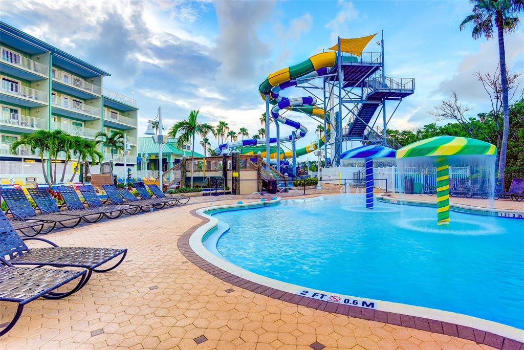 A swimming pool area features a large water slide, lounge chairs, and a mushroom fountain — 399 2ND STREET UNIT 216, INDIAN ROCKS BEACH, FL