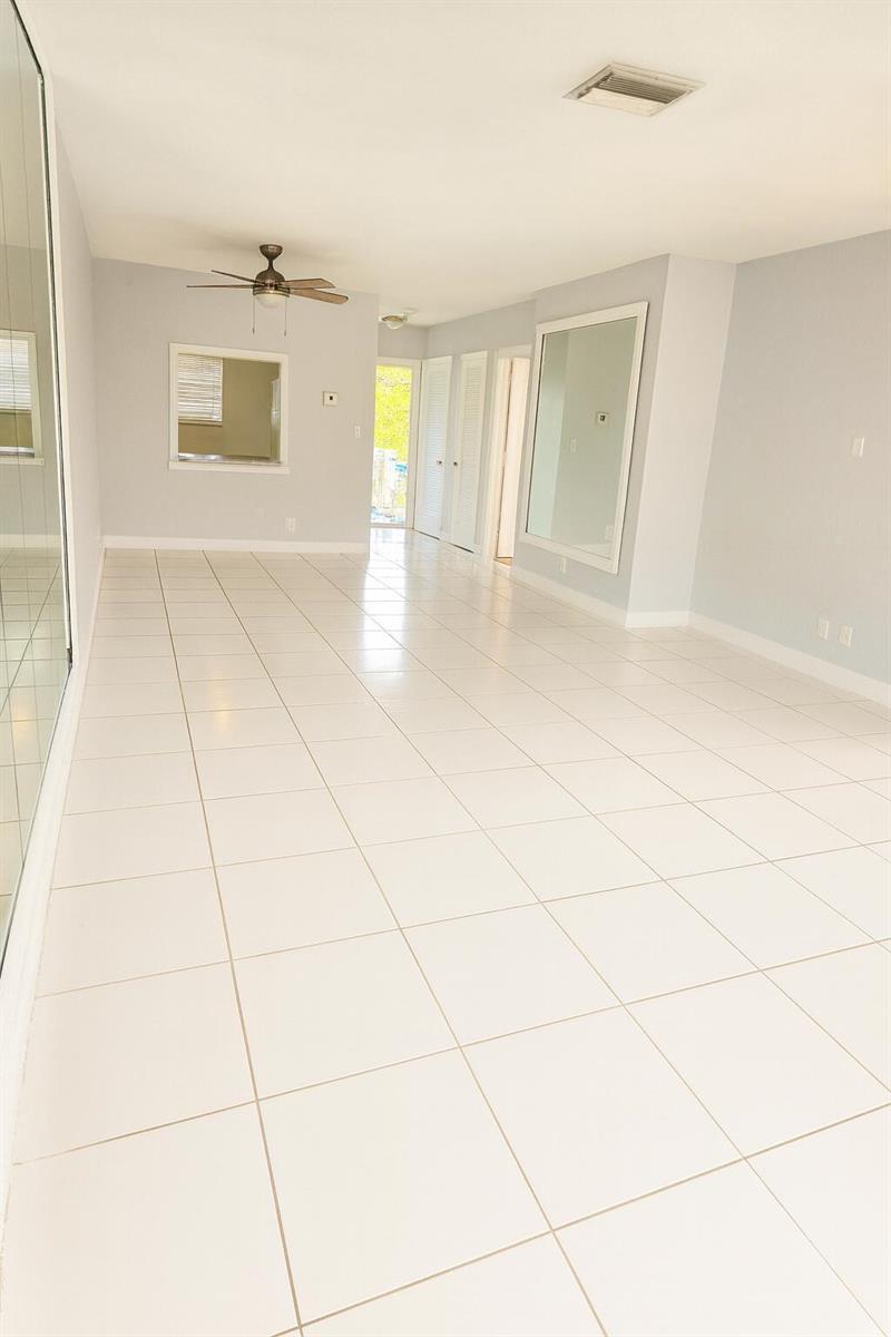 A bright, empty room features white tile flooring, light gray walls, and a ceiling fan — 1001 SE 3rd Street # 3, Deerfield Beach FL 33441, DEERFIELD BEACH, FL