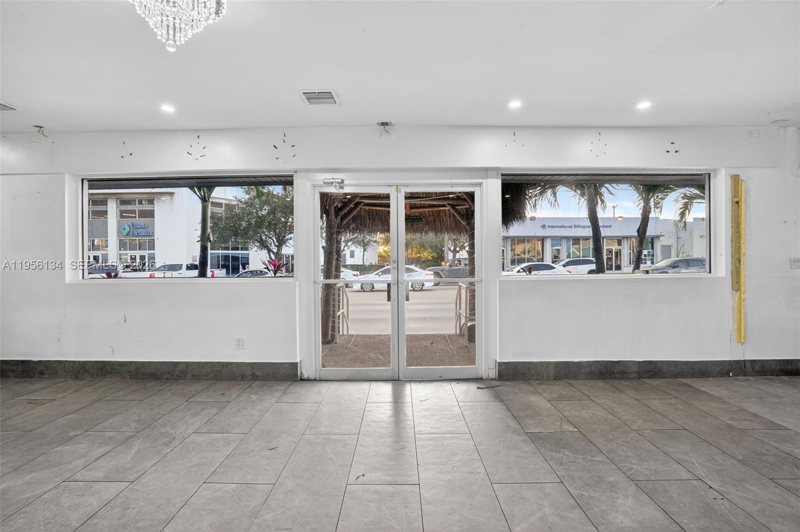 An empty commercial space features large windows, glass double doors, and gray tile flooring — 45 NW 22 AVE, FL 33125, FL