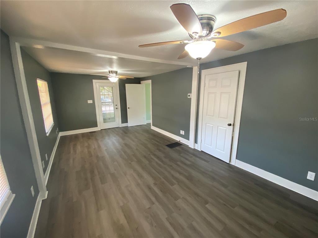 A room with dark gray walls, wood-look flooring, two ceiling fans, and white trim — 227 E BARNES AVENUE, EUSTIS, FL