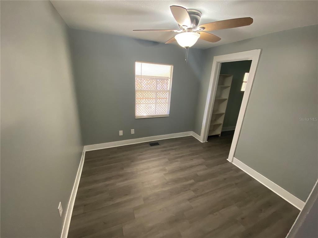 A bedroom with gray walls, wood-look flooring, a ceiling fan, and an open closet — 227 E BARNES AVENUE, EUSTIS, FL