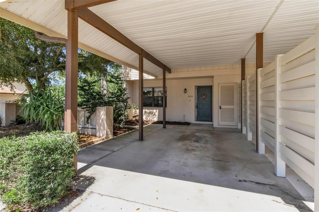 A covered carport leads to the front entrance of a single-story residential building — 3415 51ST AVENUE CIRCLE W UNIT 206, BRADENTON, FL