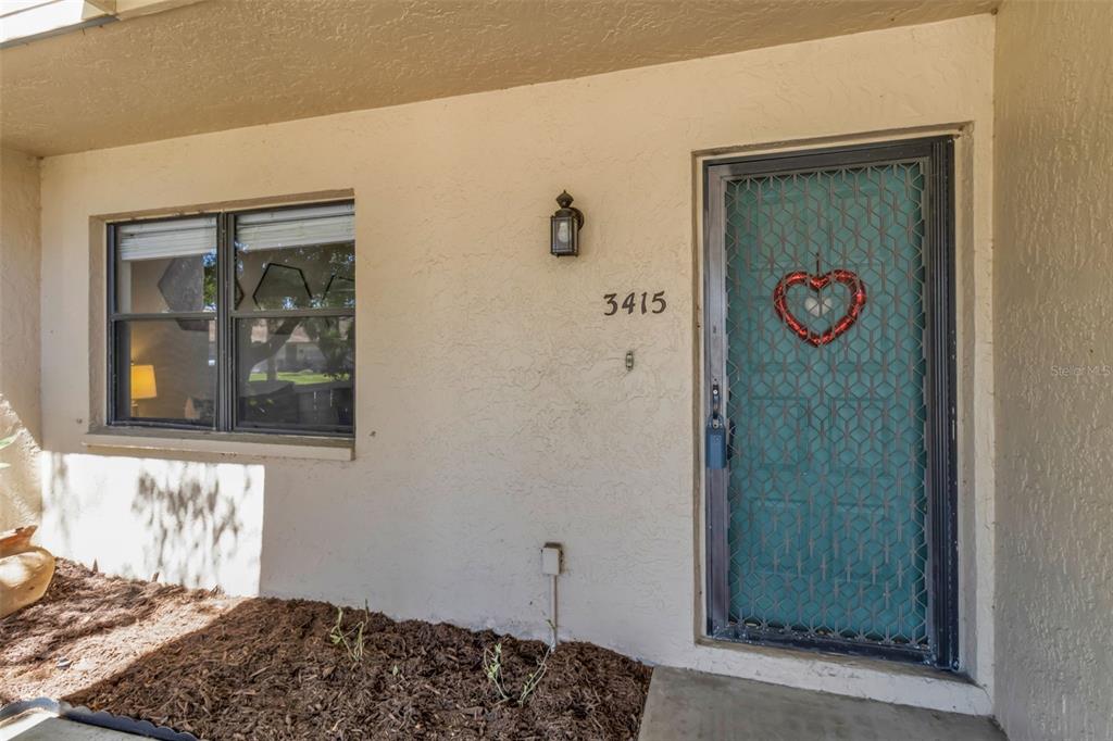 The exterior view shows a beige stucco wall with a window, house numbers, and a door — 3415 51ST AVENUE CIRCLE W UNIT 206, BRADENTON, FL