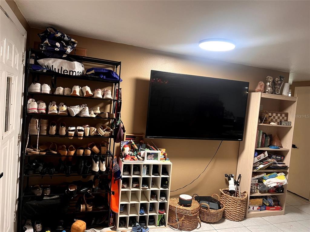 A room features a wall-mounted television, a large shoe rack, and a wooden storage shelf — 210 WALNUT AVENUE NW, PORT CHARLOTTE, FL
