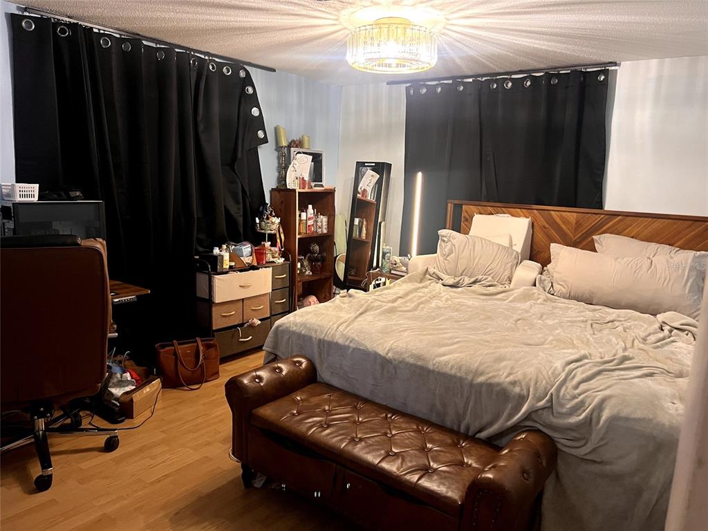 A bedroom features a bed with a wooden headboard, a leather bench, and dark curtains — 210 WALNUT AVENUE NW, PORT CHARLOTTE, FL