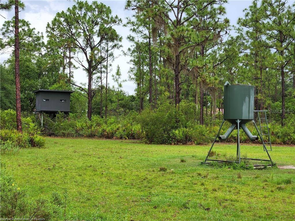 A grassy field features a raised hunting blind and a large metal game feeder — 17470 COUNTY ROAD 731, VENUS, FL