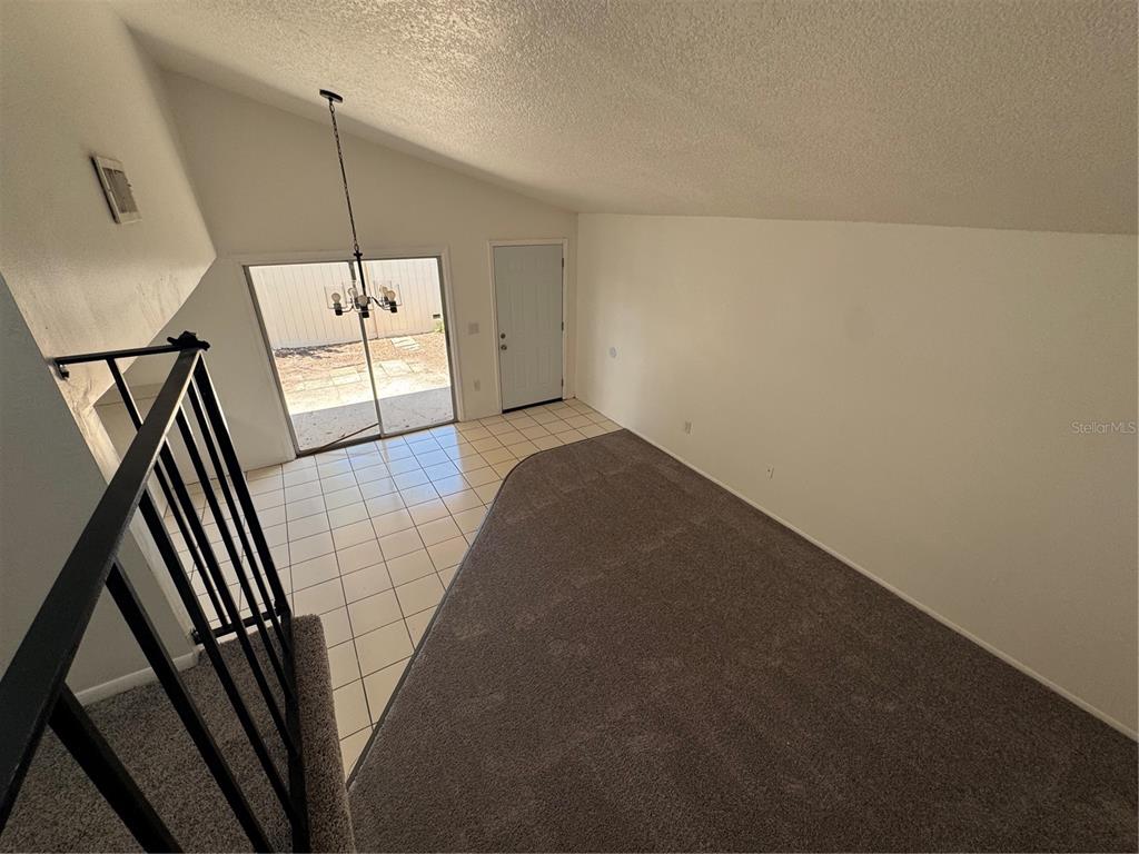 An elevated view shows a room with a carpeted area, tiled floor, and sliding glass doors — 1809 TOWNHALL LANE UNIT 1809, ORLANDO, FL