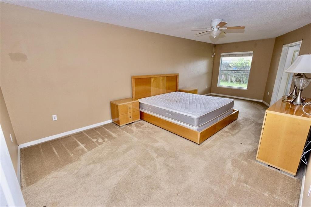 A bedroom features a platform bed, matching nightstands, a dresser, and beige carpeting — 818 CARROUSEL LANE, KISSIMMEE, FL