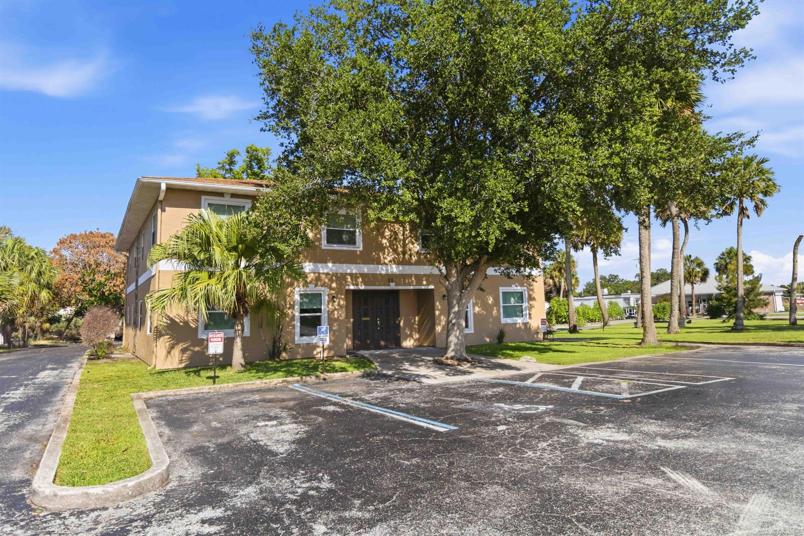A two-story tan apartment building features a large tree and a paved parking lot — 111 Scott Street, Melbourne FL 32901, MELBOURNE, FL