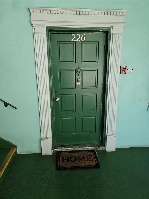 A green door with the number 226 is framed by white molding on a teal wall — 4141 NW 44TH AVENUE UNIT 226, LAUDERDALE LAKES, FL