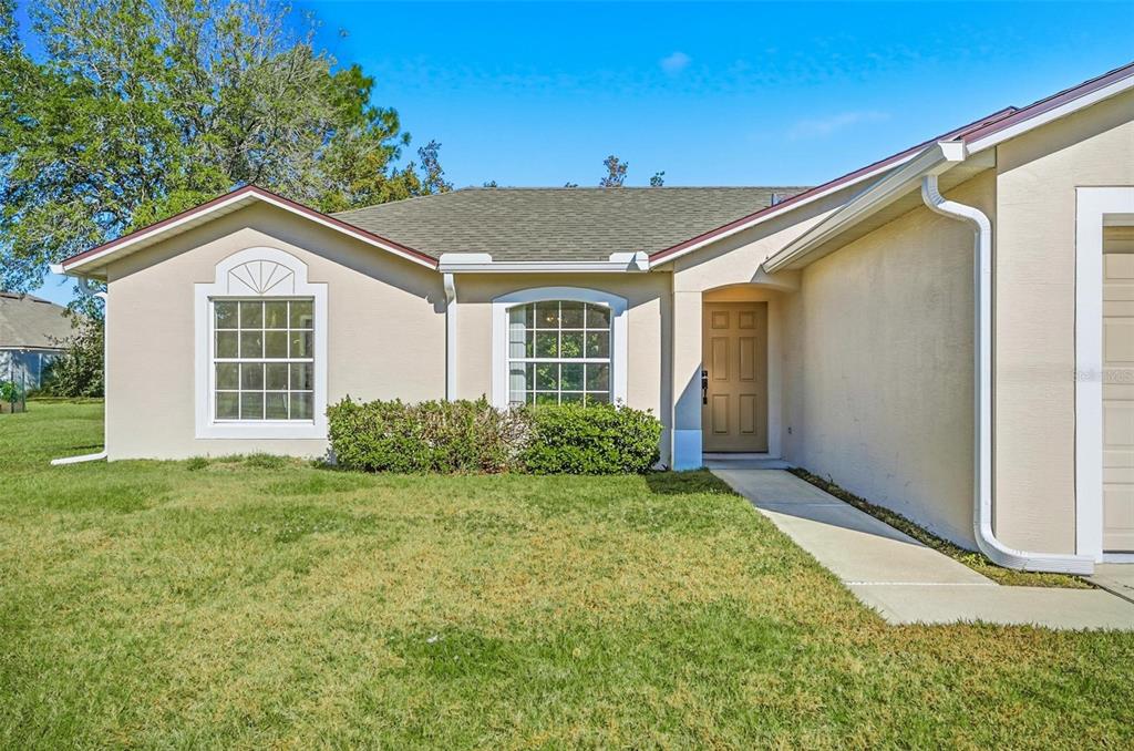 A single-story house with a tan stucco exterior, a front walkway, and two arched windows — 106 LA MANCHA DRIVE, PALM COAST, FL