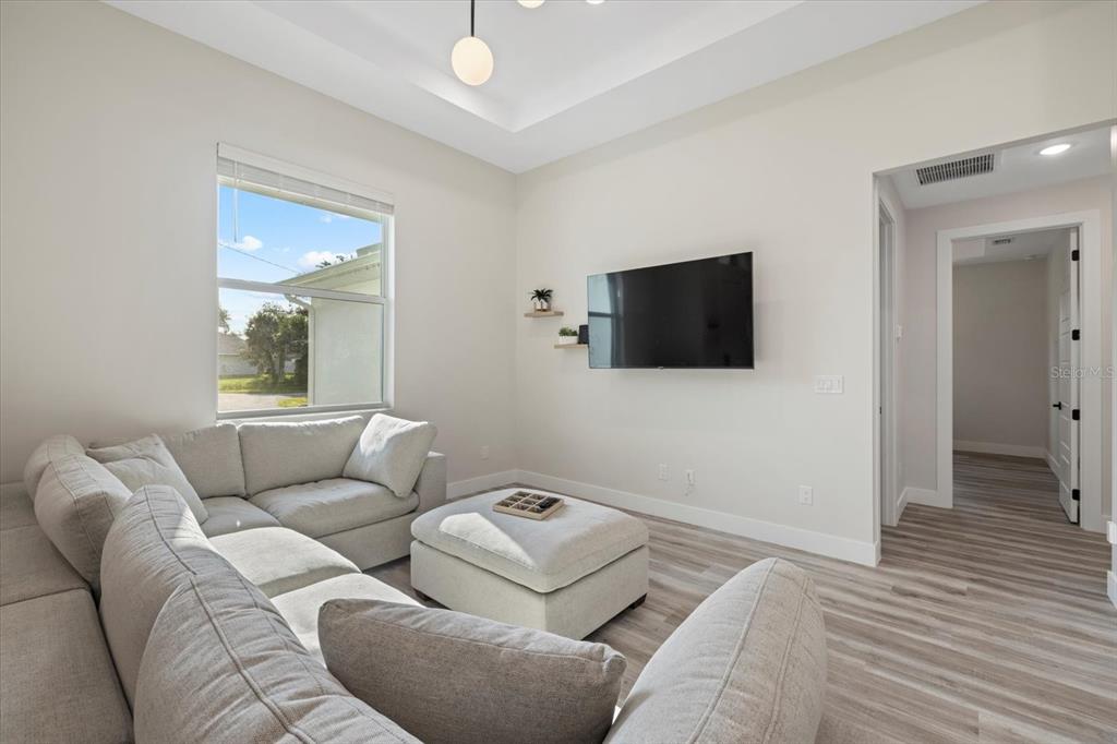 A living room features a light gray sectional sofa, a matching ottoman, and a wall-mounted television — 2938 JASON STREET, NORTH PORT, FL