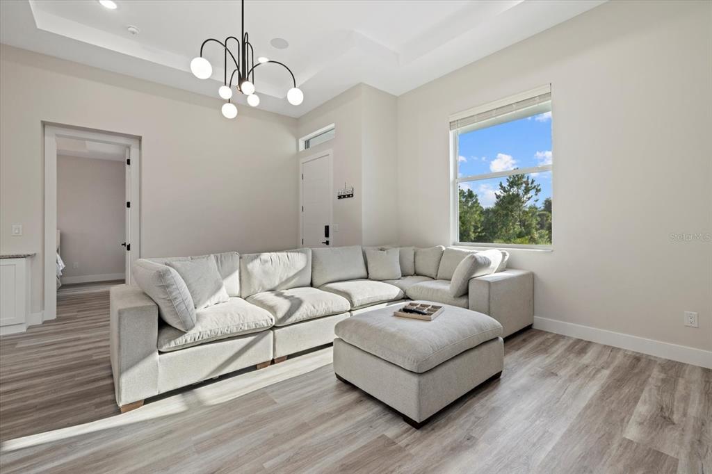 A living room features a light-colored sectional sofa, a matching ottoman, and a modern chandelier — 2938 JASON STREET, NORTH PORT, FL