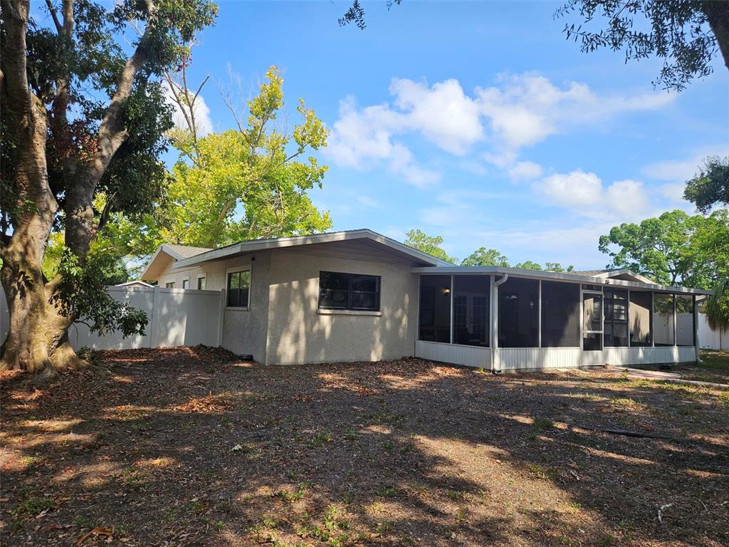 The exterior of a single-story house features a screened-in porch and a large tree — 1417 27TH STREET W, BRADENTON, FL