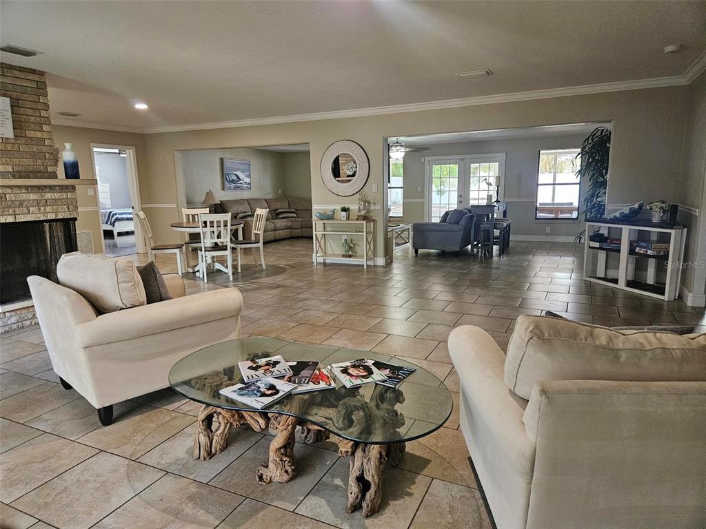 A spacious living room features tile flooring, a stone fireplace, and a glass-topped driftwood table — 1417 27TH STREET W, BRADENTON, FL