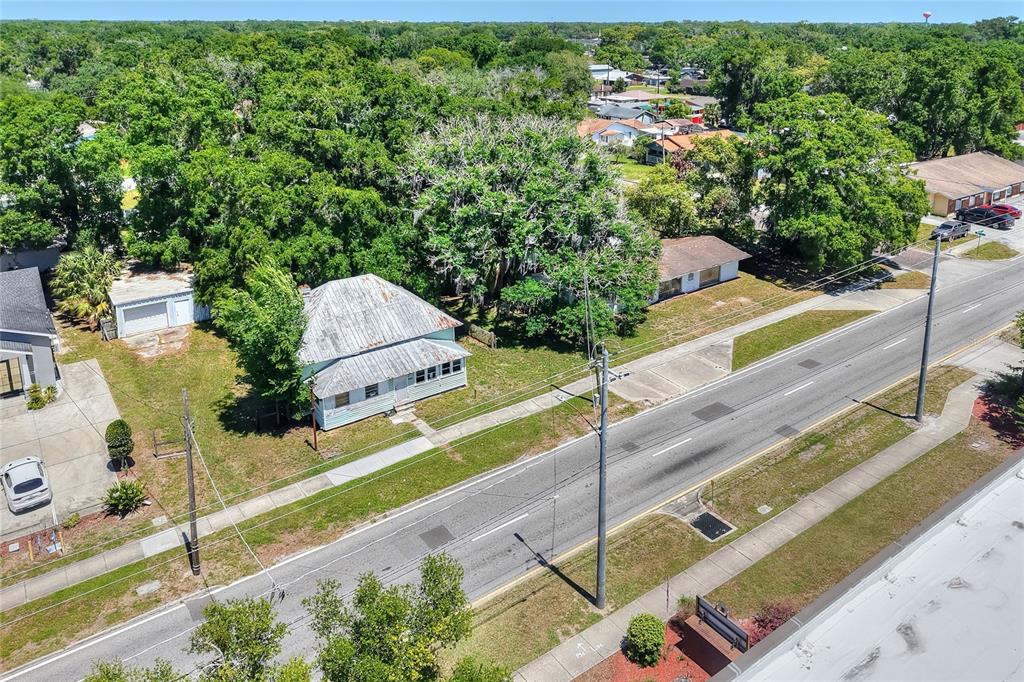 An aerial view shows a weathered house with a metal roof beside a paved road — 503 MERRIN STREET, PLANT CITY, FL