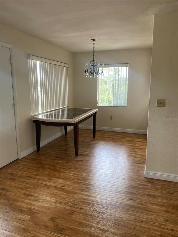 A dining area features wood-look flooring, a marble-topped table, vertical blinds, and a chandelier — 11224 82ND AVENUE UNIT 301, SEMINOLE, FL