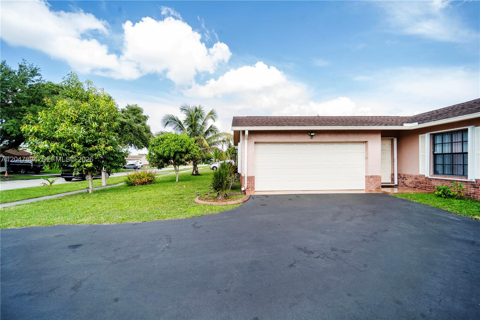 A single-story house features a white garage door, a paved driveway, and a grassy yard — 10815 NW 26th St, Sunrise FL 33322, SUNRISE, FL