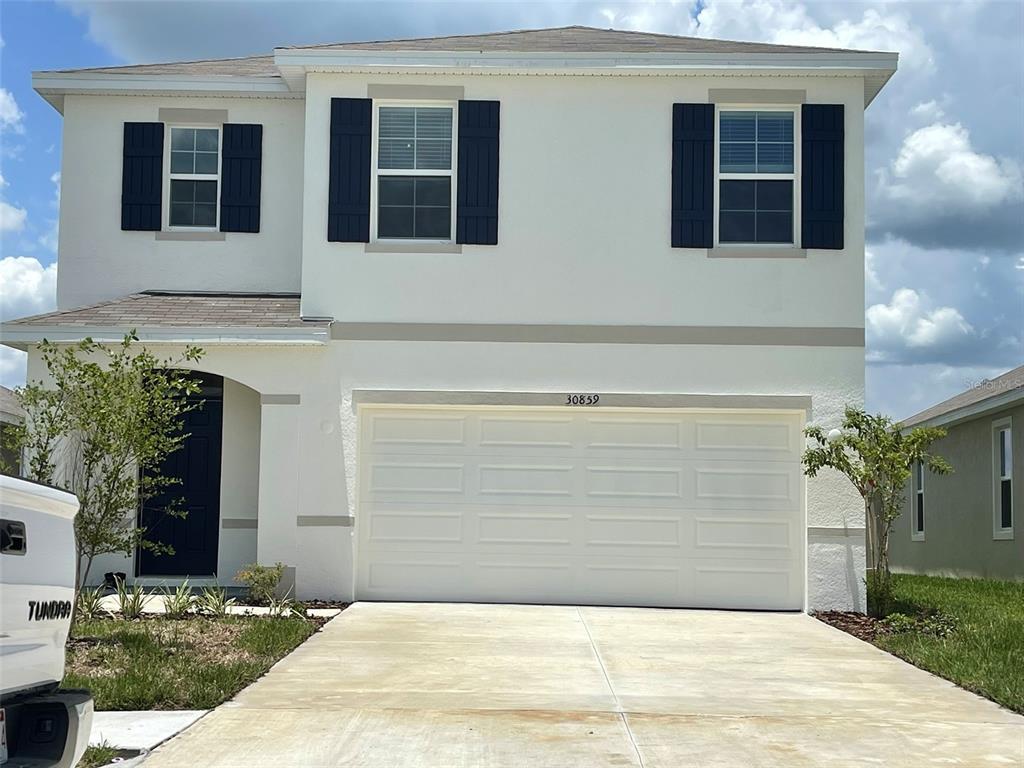 A two-story house with white stucco walls, a two-car garage, and dark blue shutters — 30859 PENNY SURF LOOP, WESLEY CHAPEL, FL