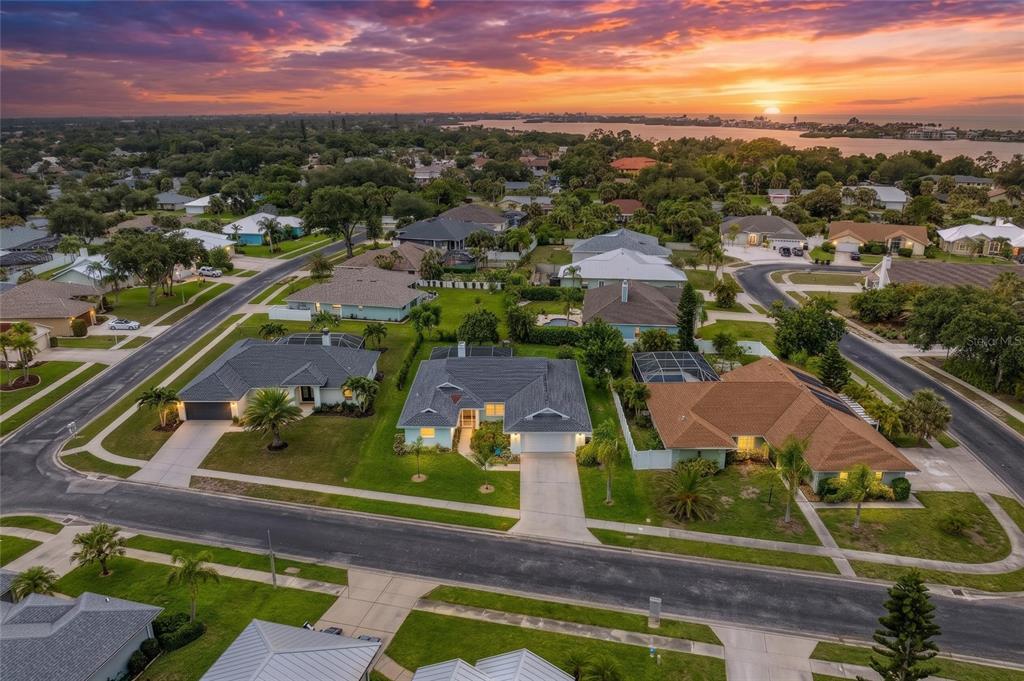 An aerial view shows suburban houses with swimming pools and palm trees at sunset — 405 BAYSIDE LANE, NOKOMIS, FL