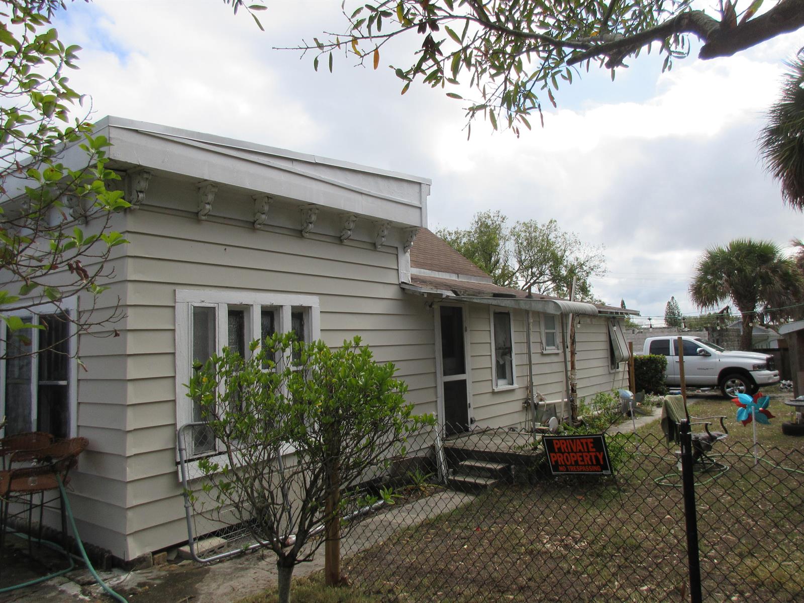 A single-story house with light-colored siding, a flat roofline with decorative brackets, and a fenced yard — 603 Avenue Avenue E, Fort Pierce FL 34950, FORT PIERCE, FL