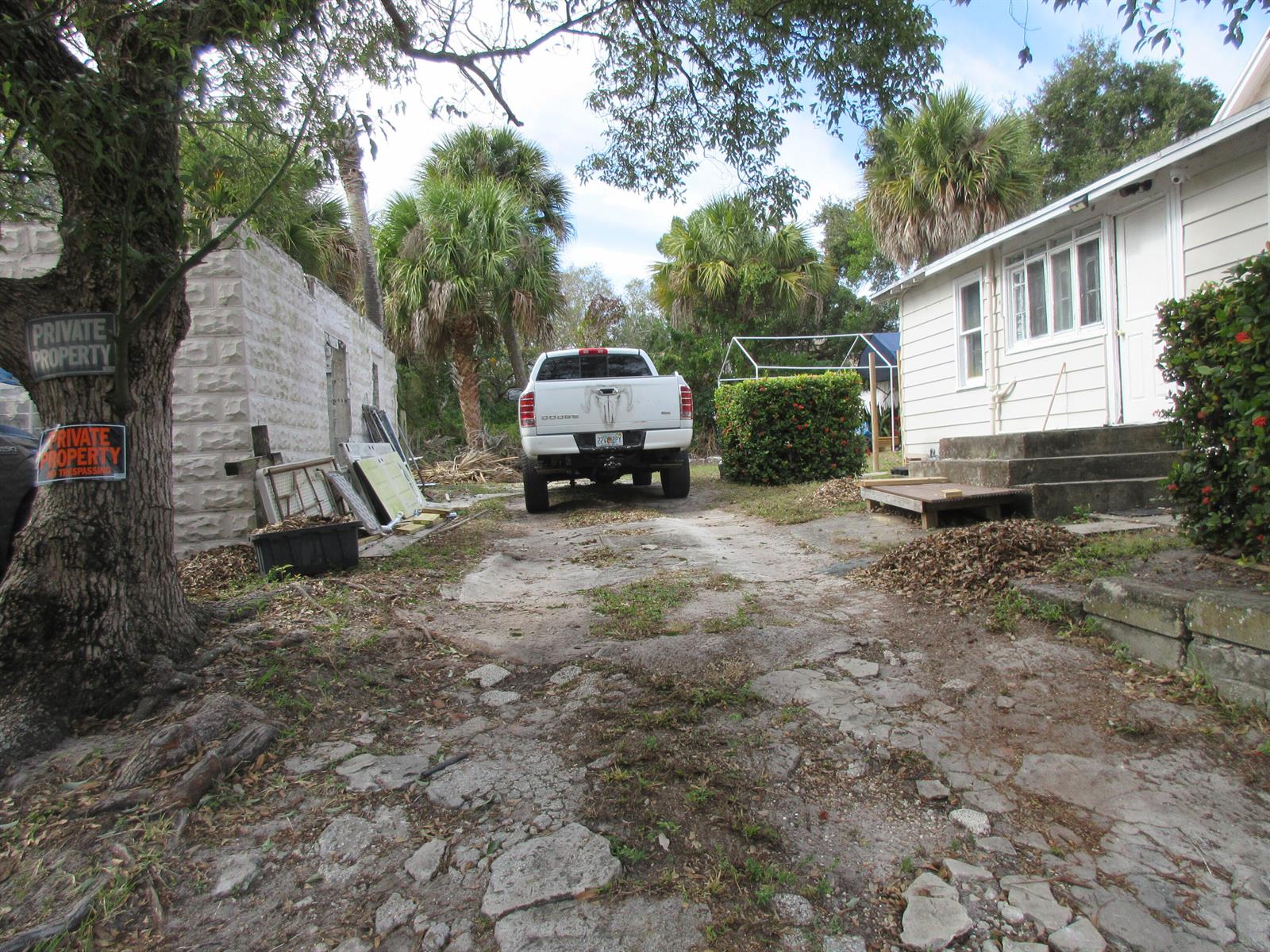 A white pickup truck is parked on a cracked driveway between a house and stone wall — 603 Avenue Avenue E, Fort Pierce FL 34950, FORT PIERCE, FL