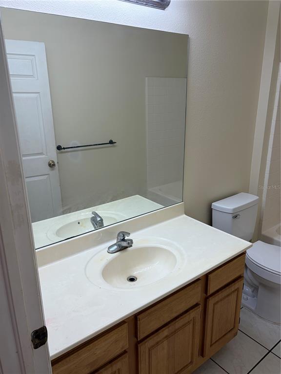 A bathroom features a vanity with a white countertop, a mirror, and a toilet — 530 BELLTOWER AVENUE, DELTONA, FL