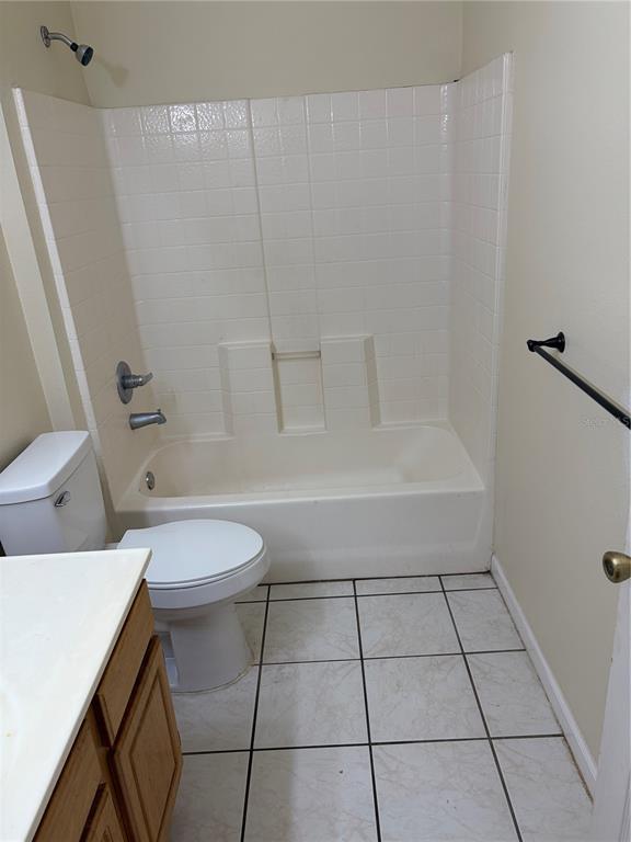 A bathroom features a white toilet, a vanity, and a tub-shower combo with tile walls — 530 BELLTOWER AVENUE, DELTONA, FL