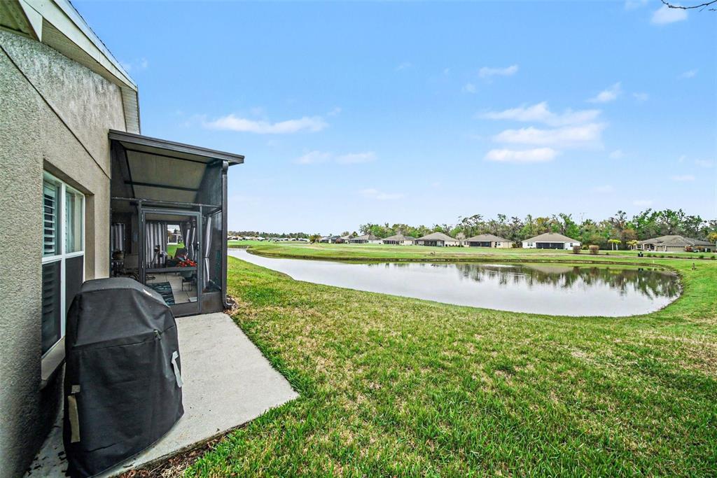 A covered patio overlooks a pond and a residential neighborhood on a sunny day — 10321 OLD TAMPA BAY DRIVE, SAN ANTONIO, FL