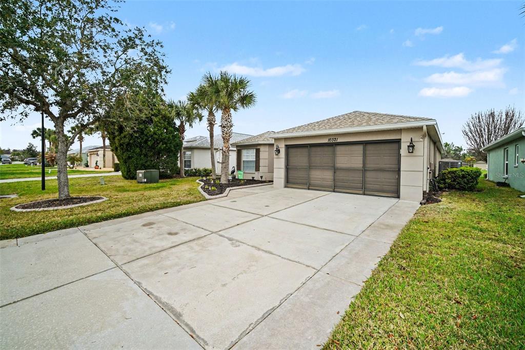 A single-story house with a concrete driveway, a two-car garage, and palm trees — 10321 OLD TAMPA BAY DRIVE, SAN ANTONIO, FL