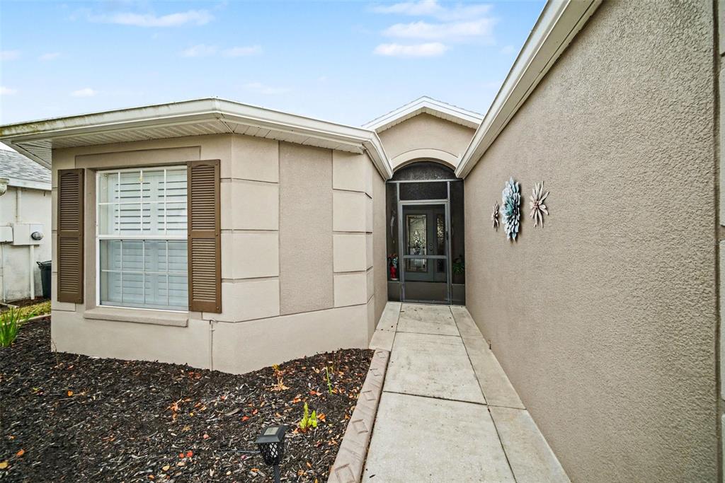 The exterior of a house features a concrete walkway leading to a screened front entryway — 10321 OLD TAMPA BAY DRIVE, SAN ANTONIO, FL