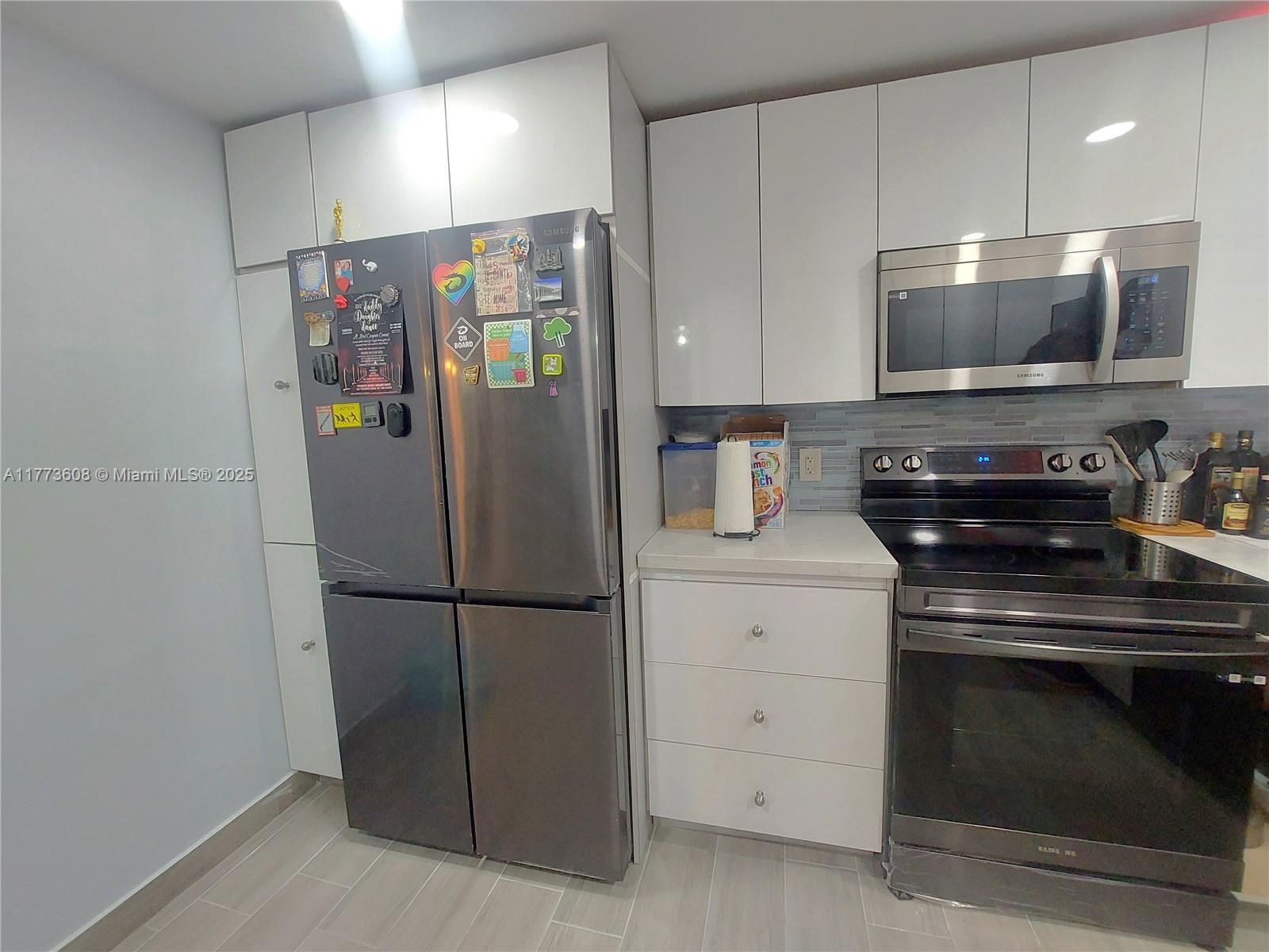 A kitchen features white cabinets, stainless steel appliances, and a gray refrigerator with magnets — 16300 Golf Club Rd Apt 317, Weston FL 33326, WESTON, FL