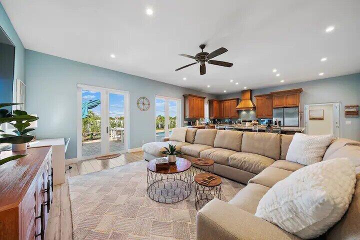 An open-concept living room features a large sectional sofa, wood cabinets, and glass patio doors — 500 Sunrise Way, Juno Beach FL 33408, JUNO BEACH, FL