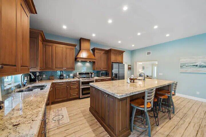 A kitchen with wood cabinets, granite countertops, a large island, and light blue walls — 500 Sunrise Way, Juno Beach FL 33408, JUNO BEACH, FL
