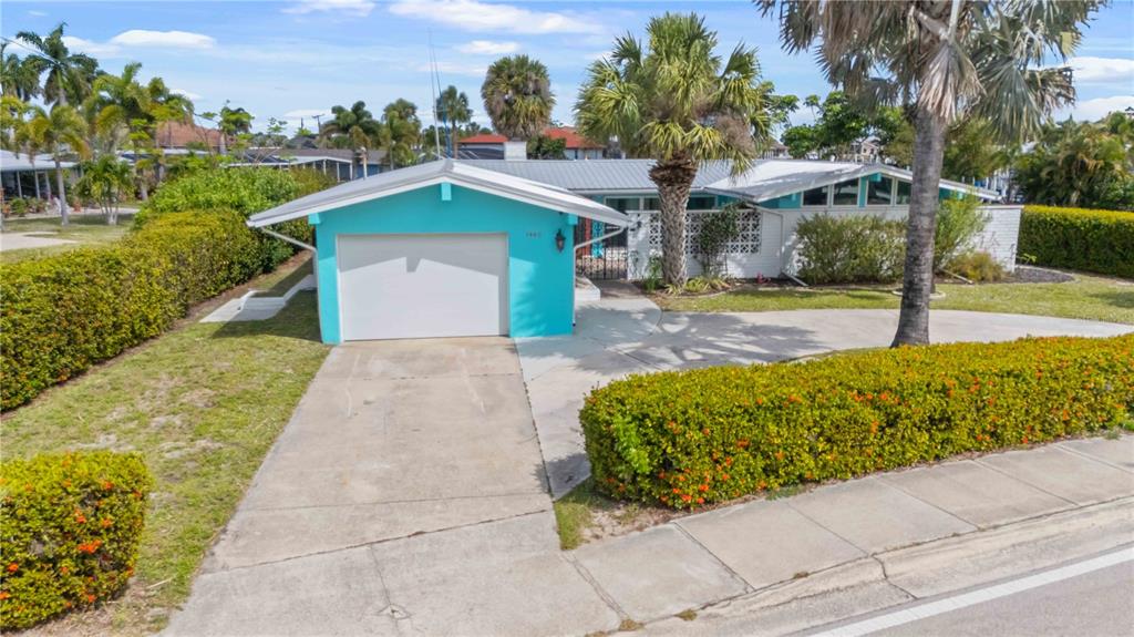 A bright turquoise single-story house features a white garage door and a concrete driveway — 1960 W MARION AVENUE, PUNTA GORDA, FL