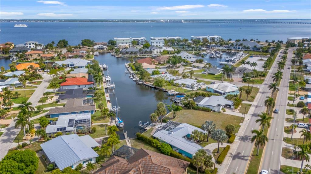 An aerial view shows waterfront homes along a canal leading to a large bay — 1960 W MARION AVENUE, PUNTA GORDA, FL