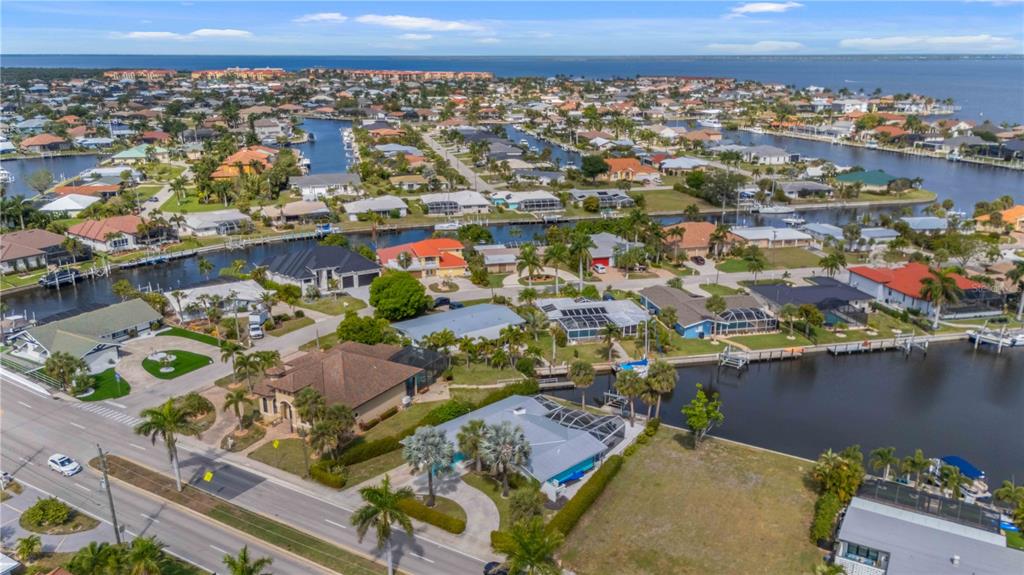 An aerial view shows waterfront houses with boat docks along canals near a large bay — 1960 W MARION AVENUE, PUNTA GORDA, FL