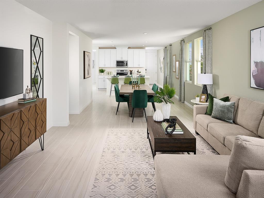 An open-concept living and dining area features light tile flooring, a kitchen, and modern furniture — 5305 WILLOW CREEK, HAINES CITY, FL