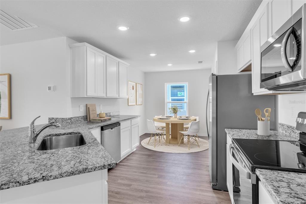 A kitchen with white cabinets, granite countertops, stainless steel appliances, and an adjacent dining area — 13 PRINCE ANTHONY LANE, PALM COAST, FL